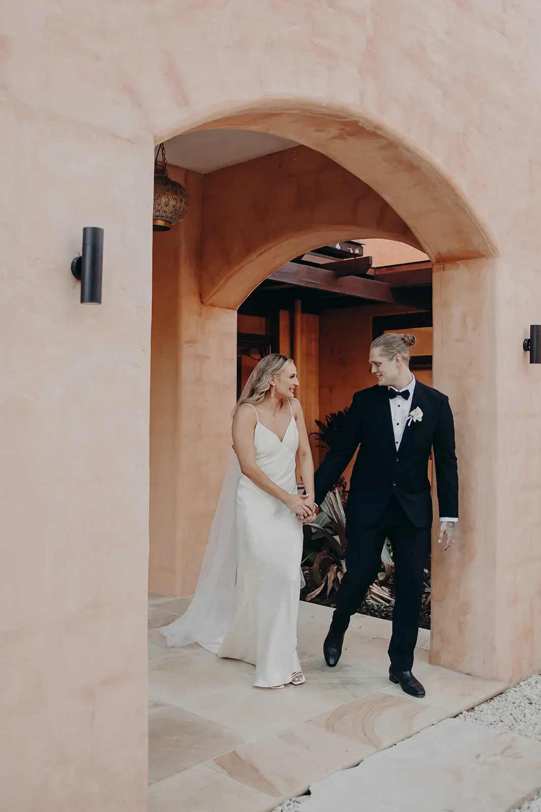 monique_josh_newlyweds_walk_archway_7eded3c760