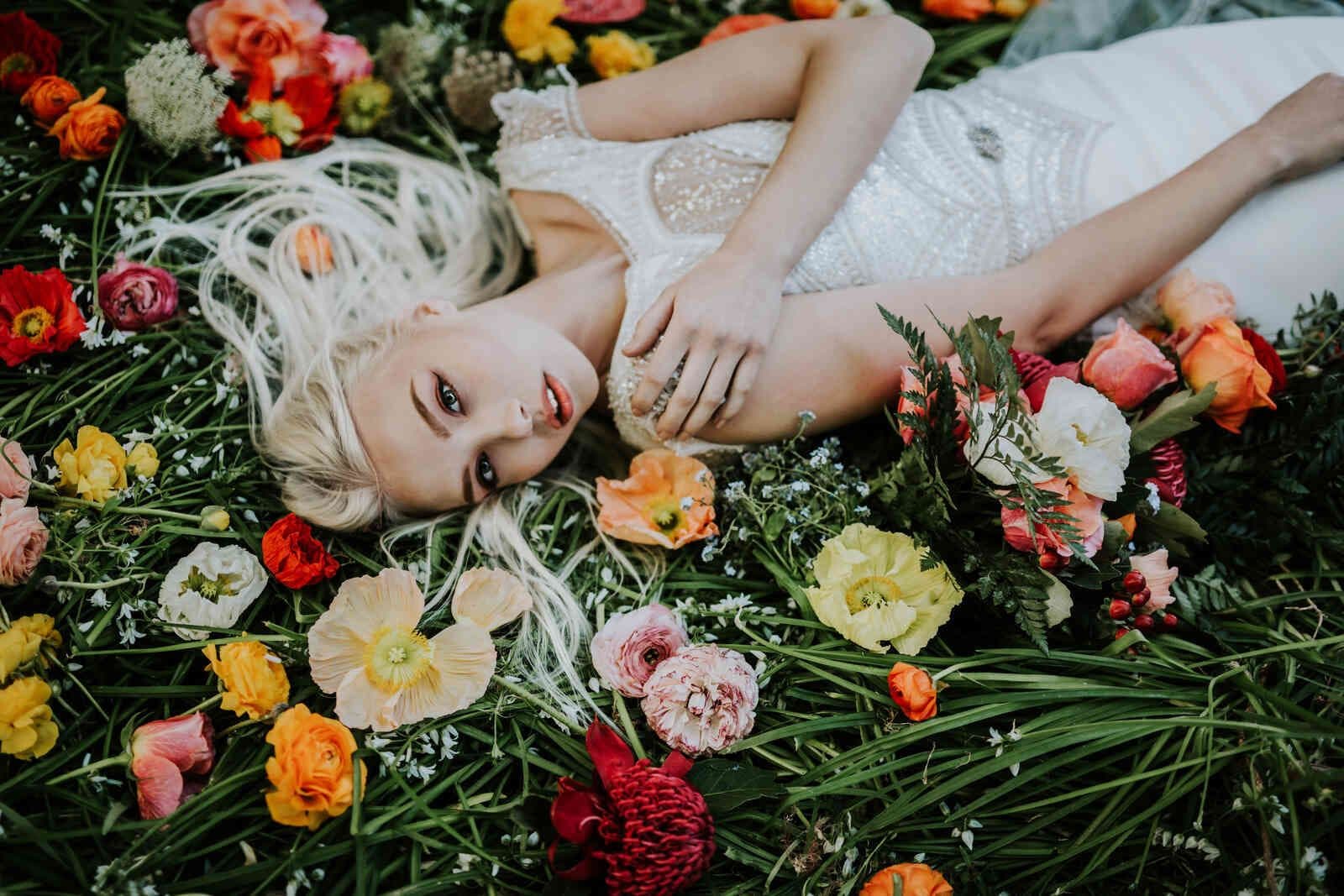 bride_lying_in_grass_full_shot_colorful_flowers_8553577e64