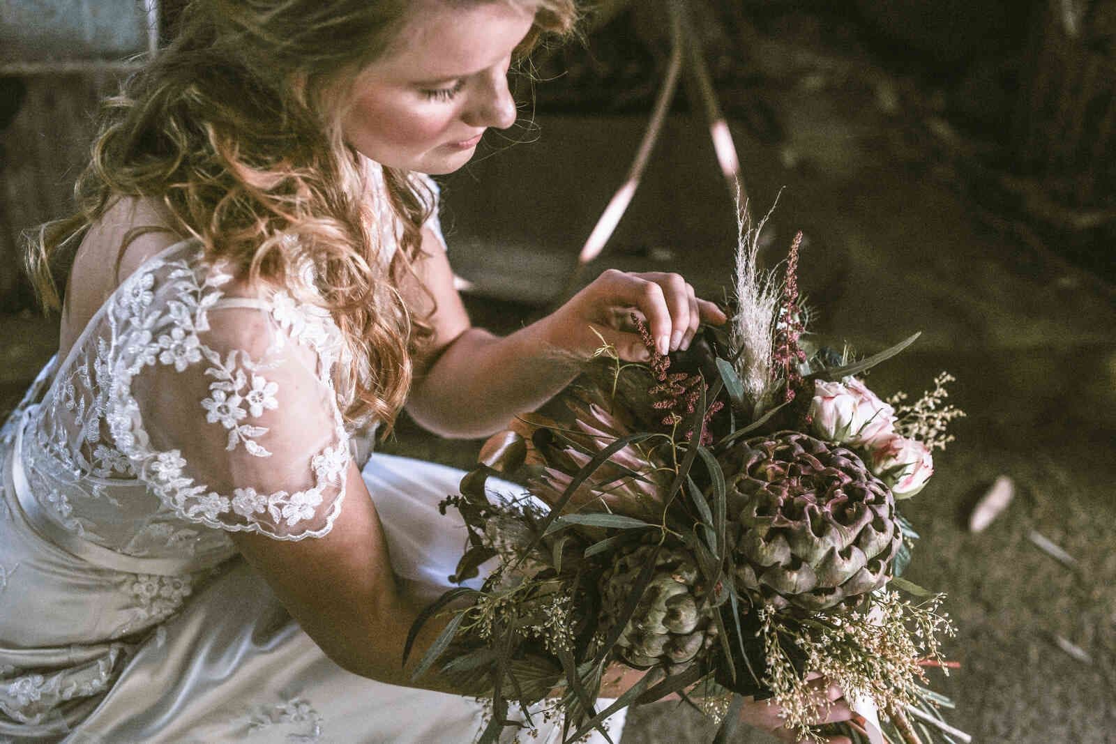 bride_adjusting_protea_artichoke_bouquet_close_0c129d6b90