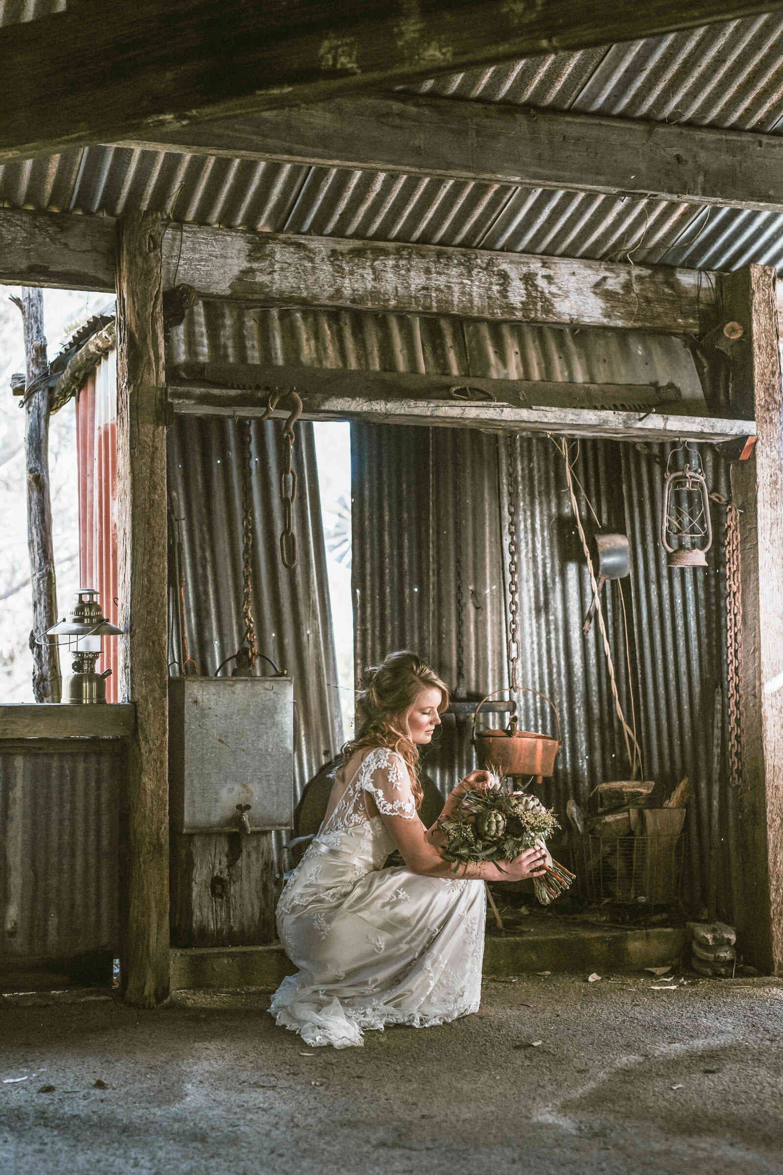 rustic_barn_bride_kneeling_pensive_portrait_7b467e2a01