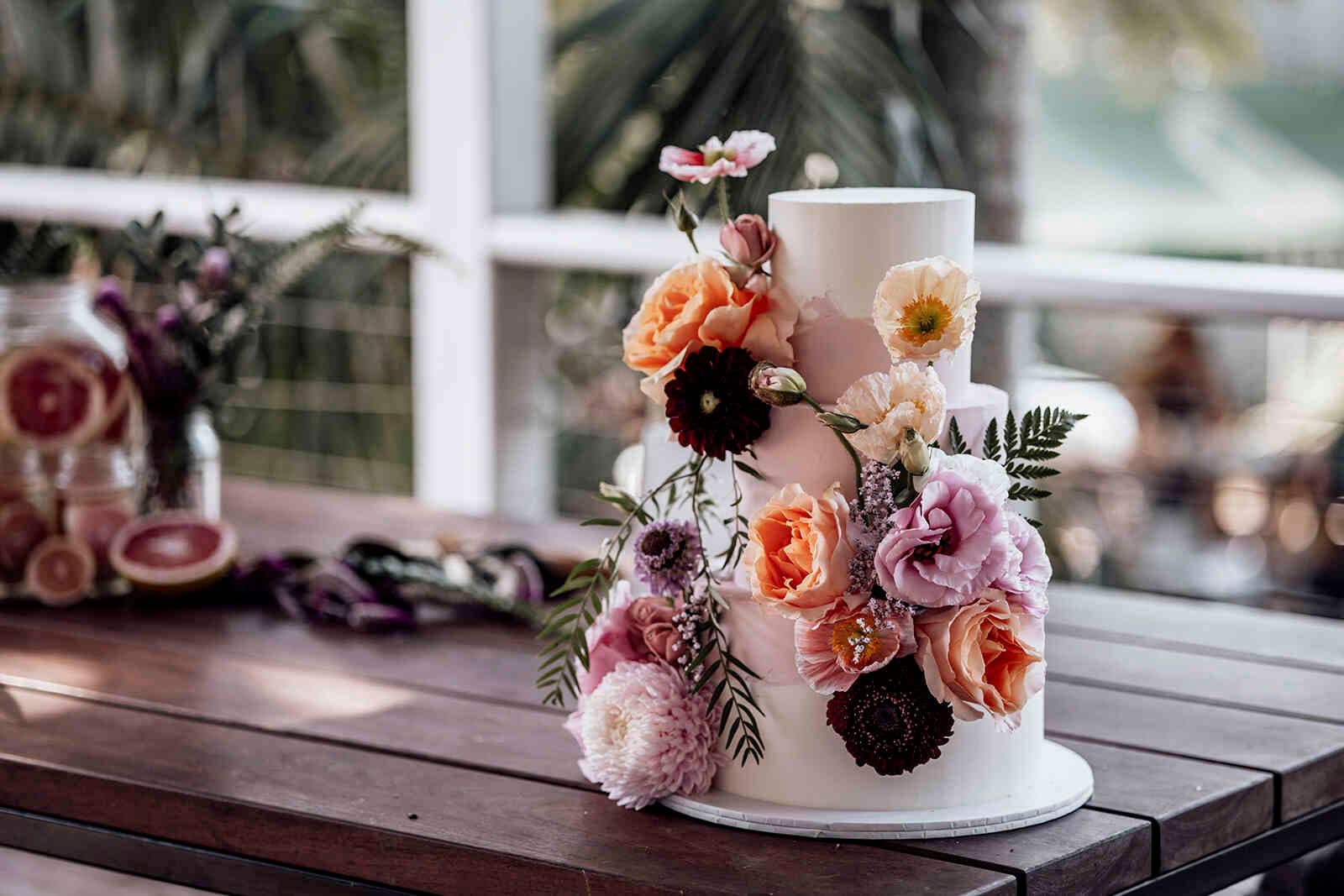 floral_decorated_wedding_cake_on_wooden_outdoor_table_8f9f54f91c