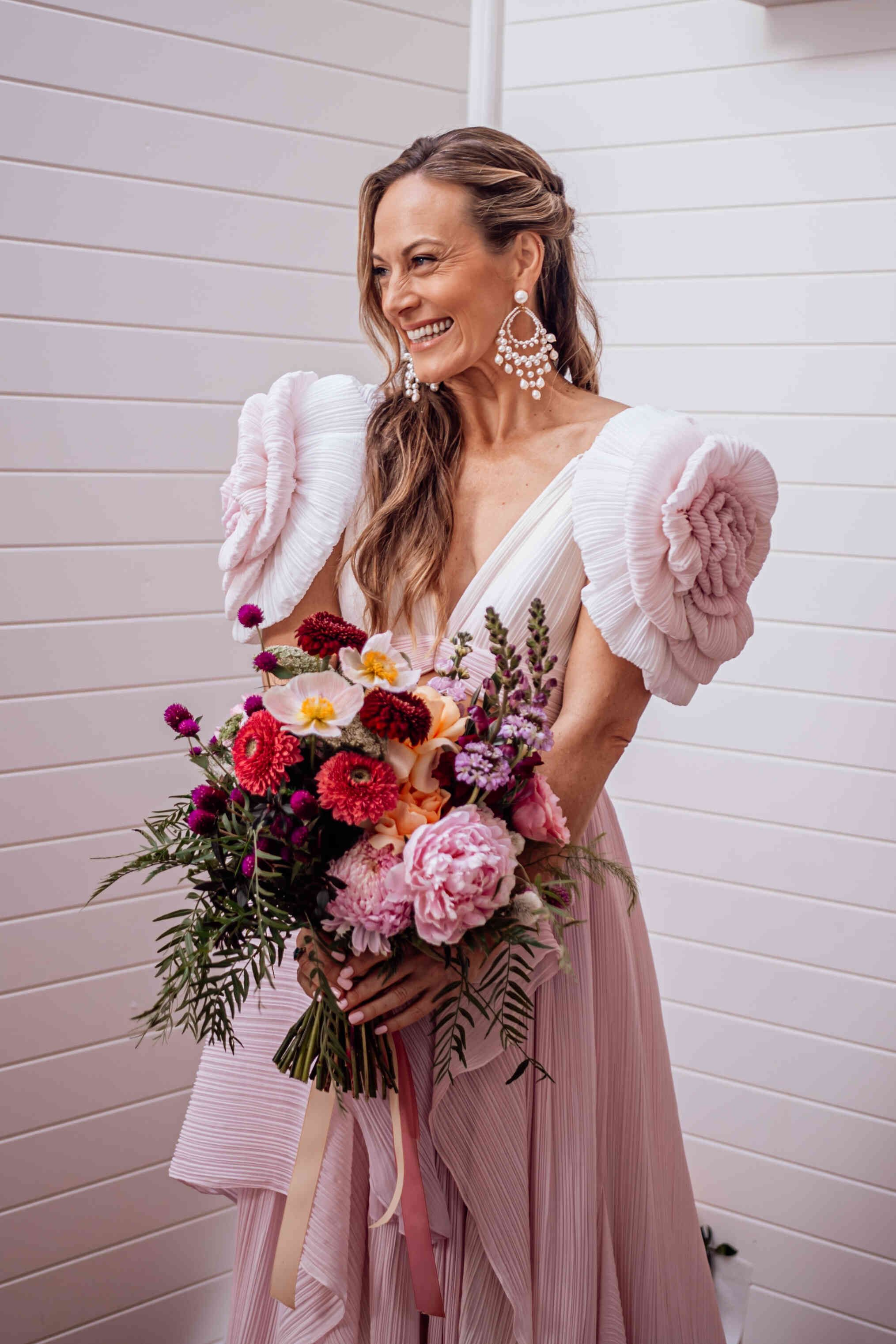 bride_holding_large_colorful_bouquet_pink_ruffle_sleeves_974e1249e0